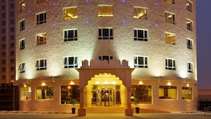 A hotel with a prominent sign in Arabic and English, multiple windows, and a well-lit entrance. - Al Safir Hotel & Tower (Manama)
