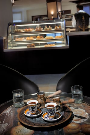 A table with a tray of pastries, two cups of coffee, and a pitcher of water. - Al Safir Hotel & Tower (Manama)