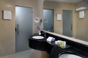 Un baño moderno con un lavabo negro, dos espejos y un perchero para toallas.