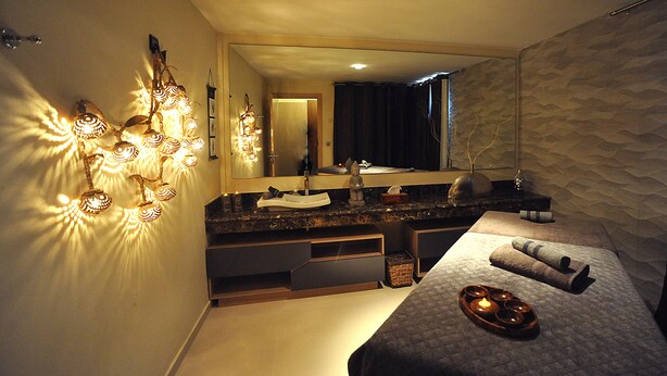 Een moderne slaapkamer met een groot bed, een kaptafel met spiegel en een wandlamp.