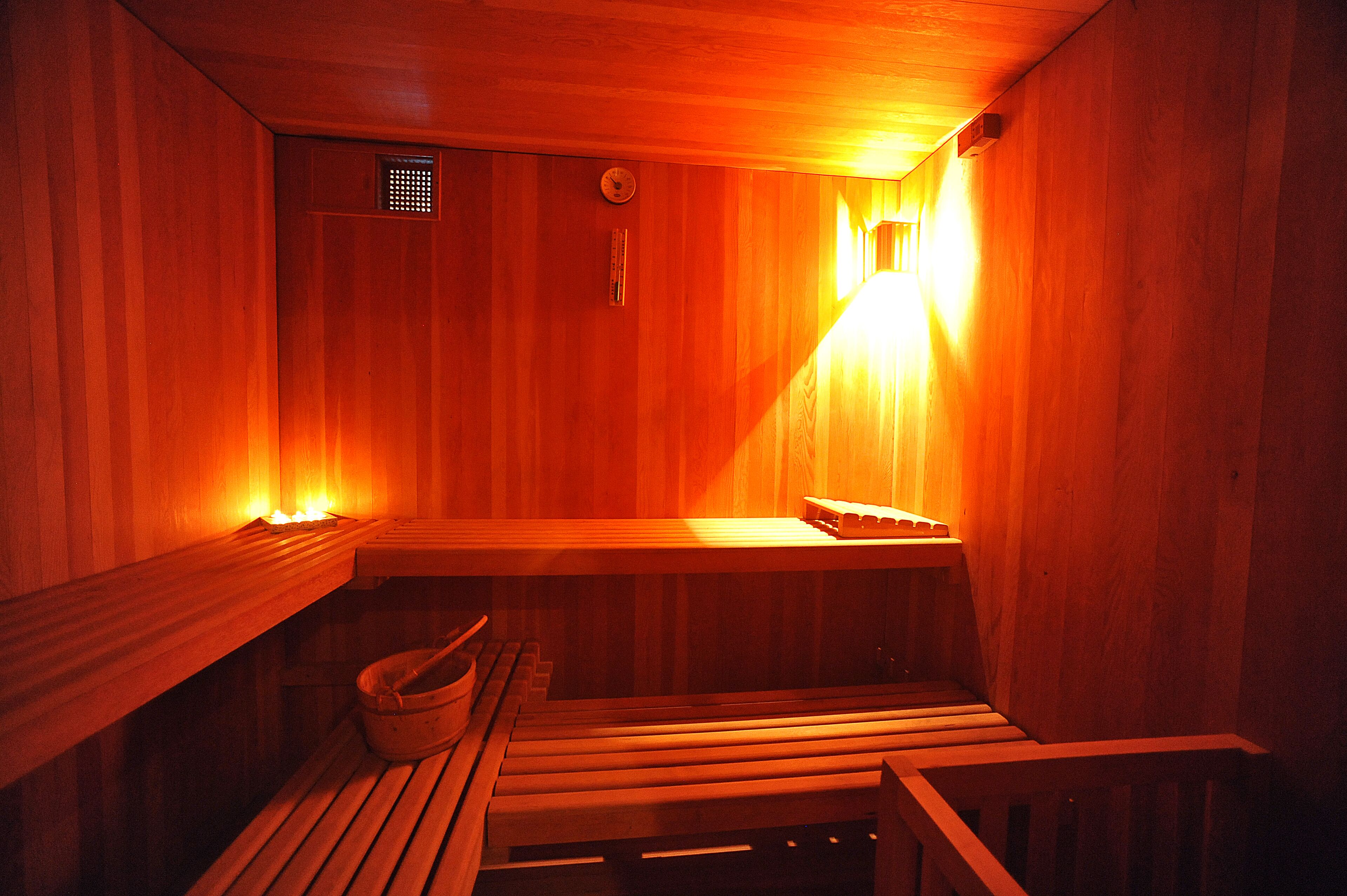 A wooden sauna with benches and a bench with a bucket.