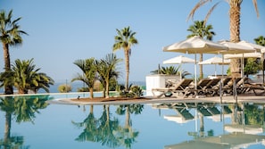 A pool area with lounge chairs and umbrellas, surrounded by palm trees and a clear sky. - Bahia Principe Escape Tenerife - Adults Only +16 Newly Renovated! (Adeje)