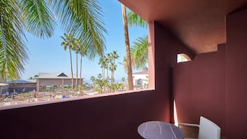 A balcony with a view of palm trees and a building.