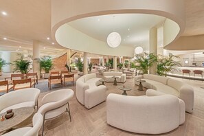 A spacious lobby with a central staircase, multiple seating areas, and large windows. - Bahia Principe Escape Tenerife - Adults Only +16 Newly Renovated! (Adeje)