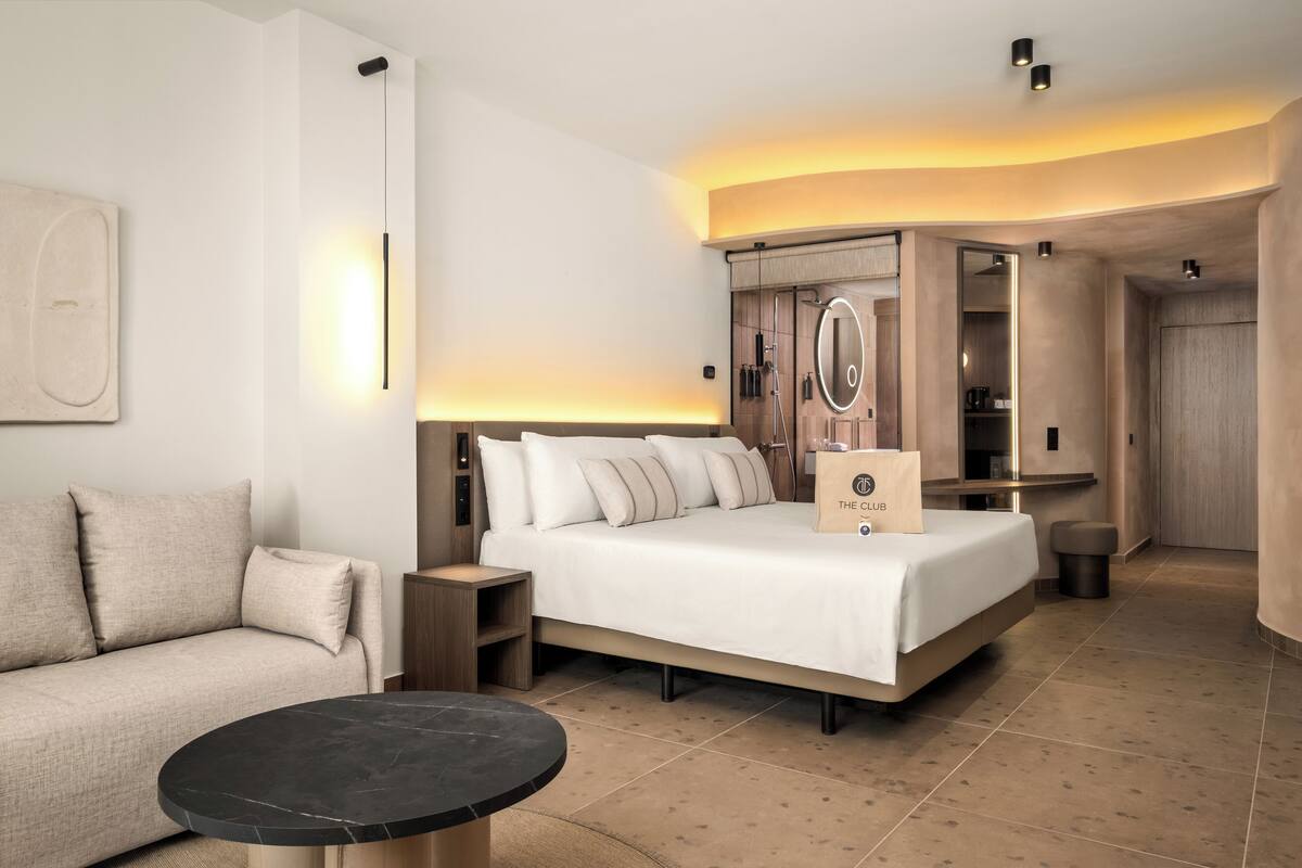 Ein modernes Hotelzimmer mit einem großen Bett, einer Couch, einem kleinen Tisch und einem Kleiderschrank.