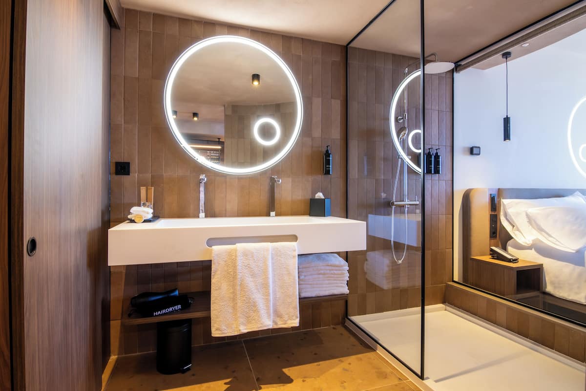 Un baño moderno con un espejo grande, un lavamanos y una cabina de ducha de vidrio.