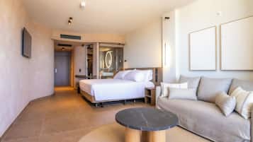 Una habitación de hotel moderna con una cama, un sofá, una mesita redonda y un vestidor.