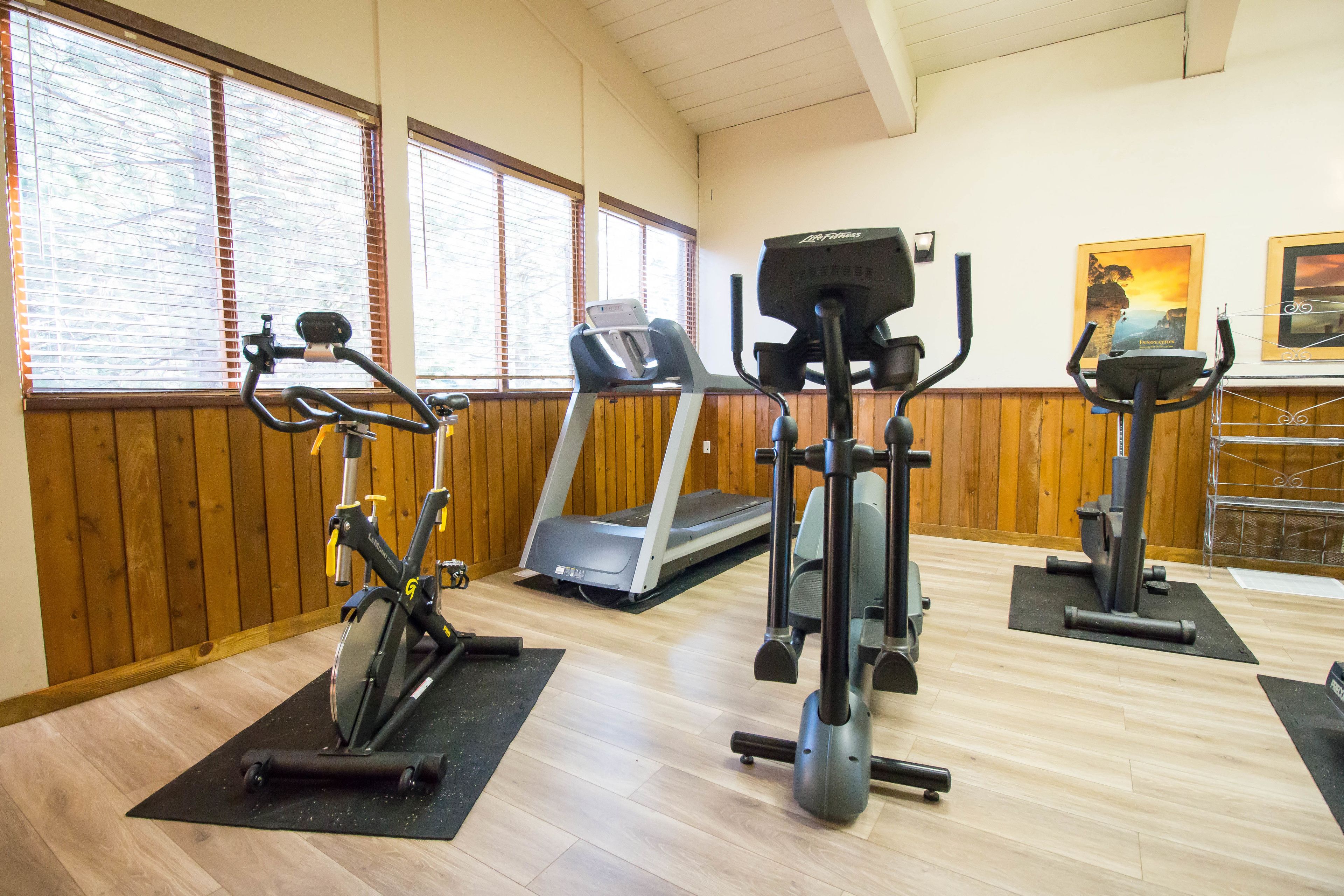 A gym with exercise equipment including a stationary bike, elliptical, and treadmill.