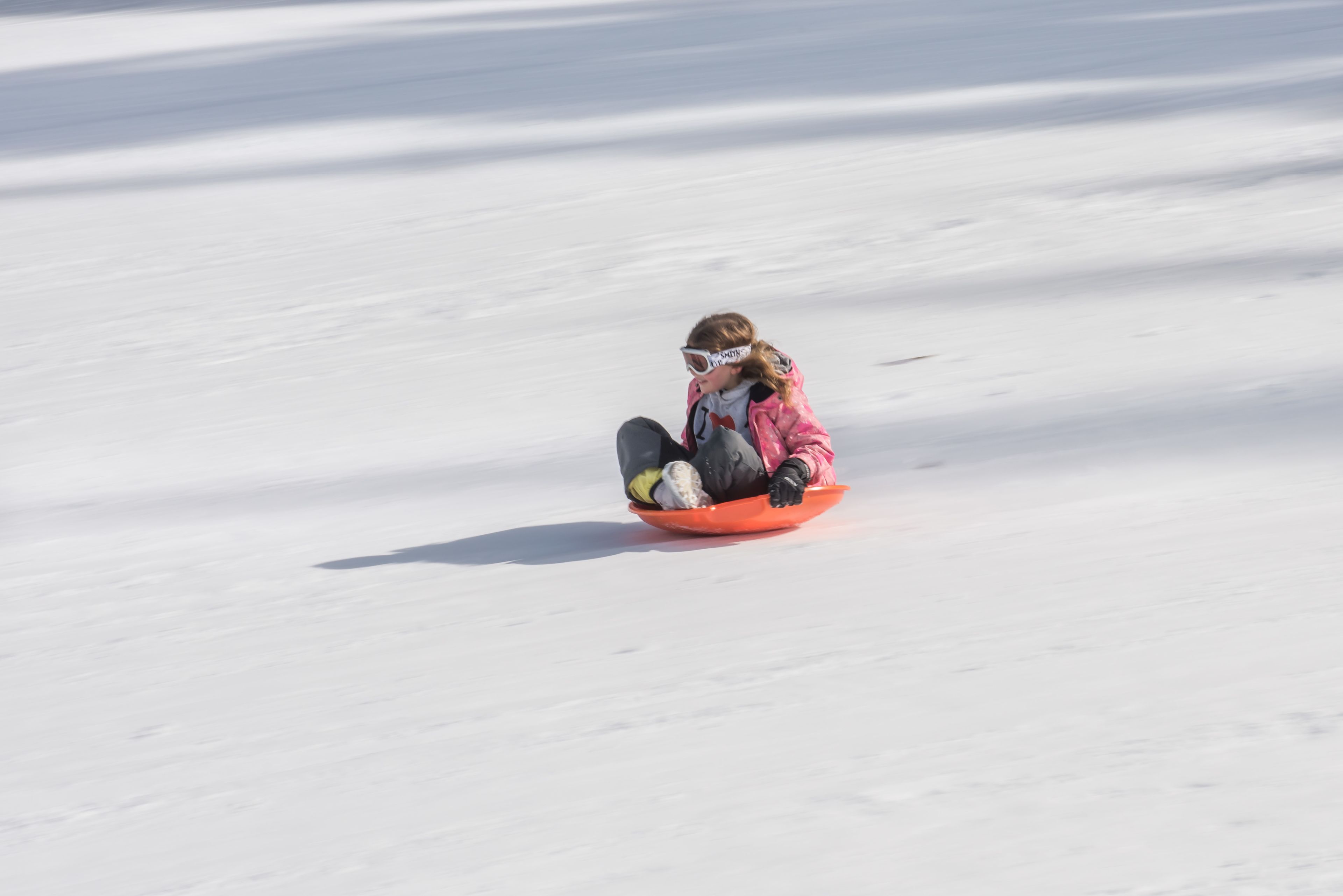 Une personne dévale une pente enneigée en luge.