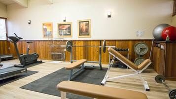 A gym with exercise equipment, a treadmill, and a bench.