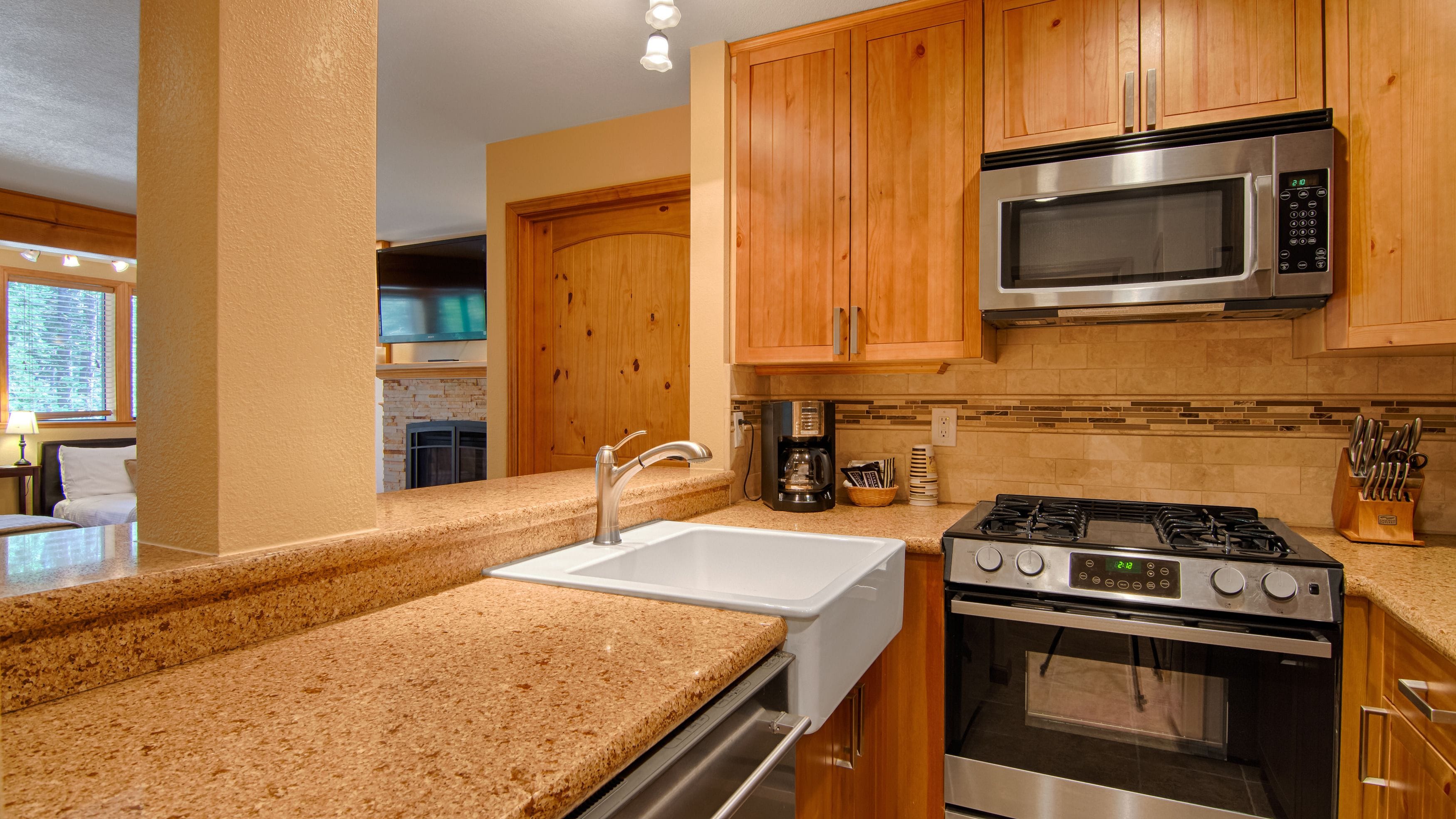 A kitchen with granite countertops, stainless steel appliances, wooden cabinets, and a built-in microwave.
