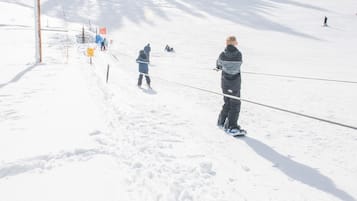 A snowy ski slope with skiers and a ski lift.