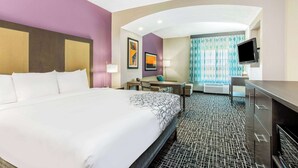 A hotel room with a large bed, a desk, a chair, a television, and a window with curtains. - La Quinta Inn & Suites by Wyndham Hillsboro (Hillsboro)