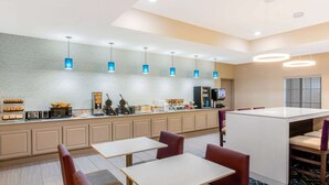 A modern hotel lobby with a long counter, seating area, and a television. - La Quinta Inn & Suites by Wyndham Hillsboro (Hillsboro)