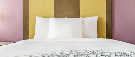 A bed with white bedding and a geometric-patterned throw.