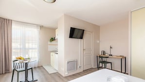 Una camera d'albergo con un letto, una scrivania, una sedia, una televisione e un angolo cottura.