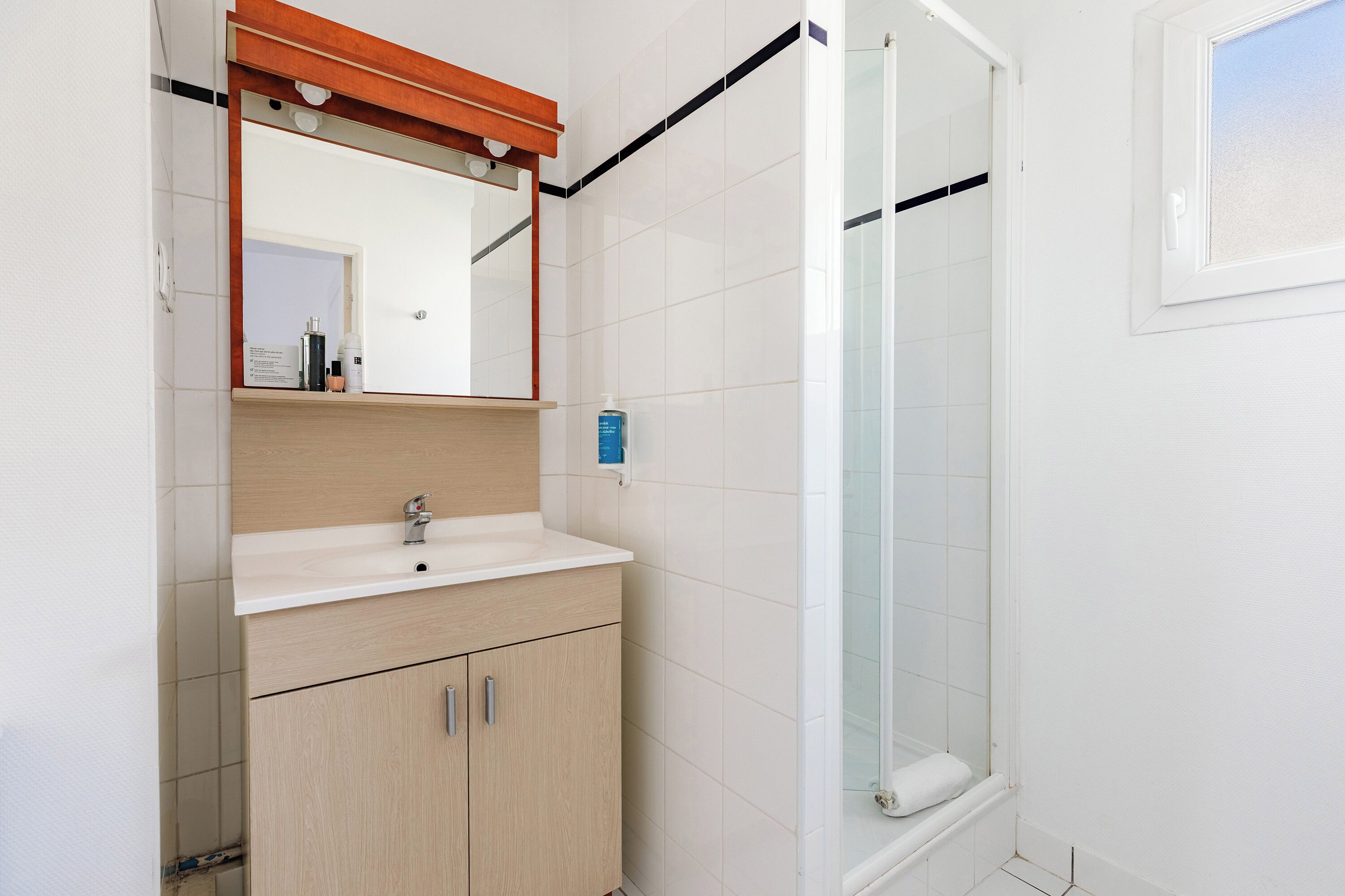A bathroom with a sink, mirror, and shower.