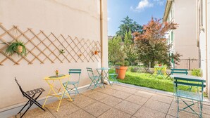 Un patio con un muretto a graticcio, un tavolino con sedie e una pianta in vaso.