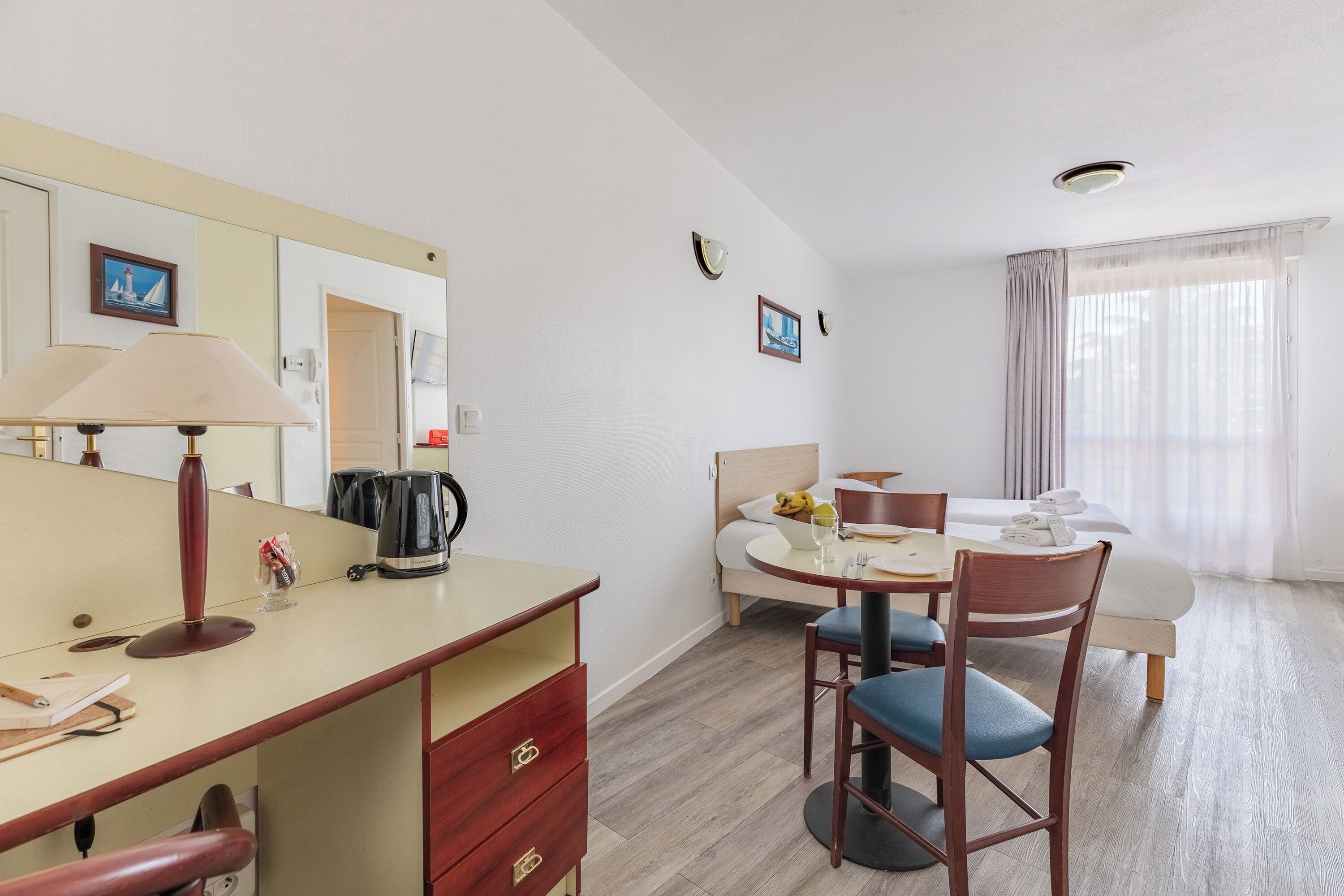 Une chambre d’hôtel comprenant un coin repas, un lit, un bureau avec une lampe et une machine à café.
