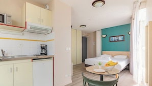 Una camera d'albergo compatta con angolo cottura, un letto, zona pranzo e bagno.
