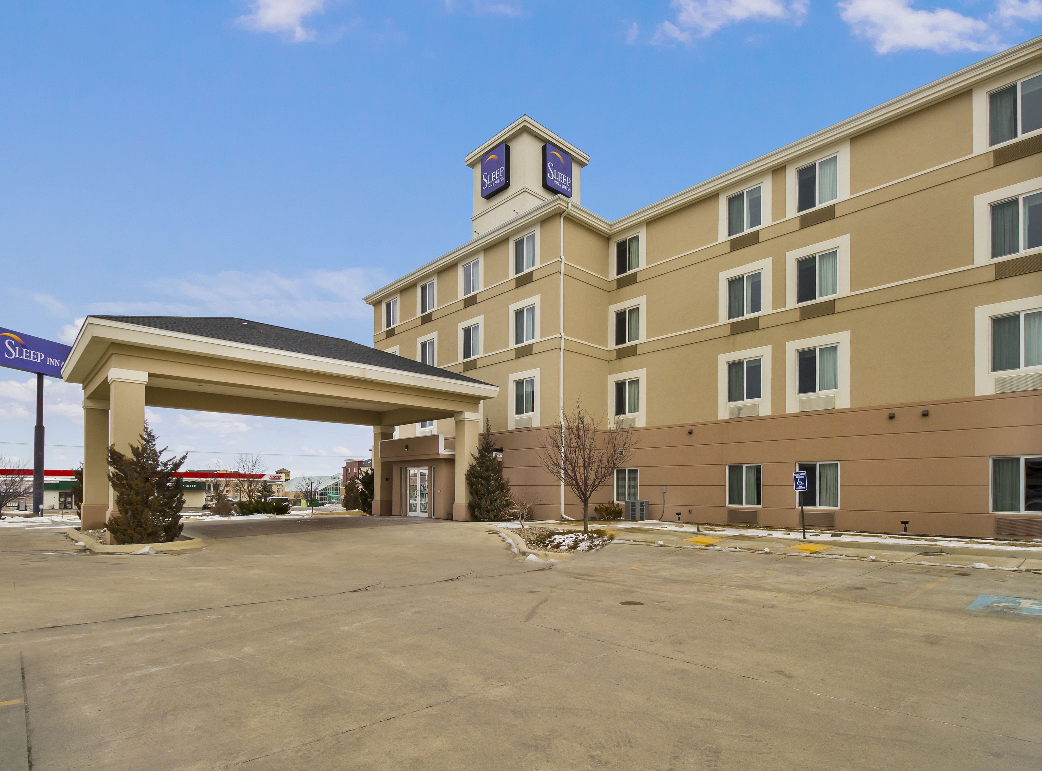 A multi-story hotel with a covered entrance, multiple windows, and a parking lot.
