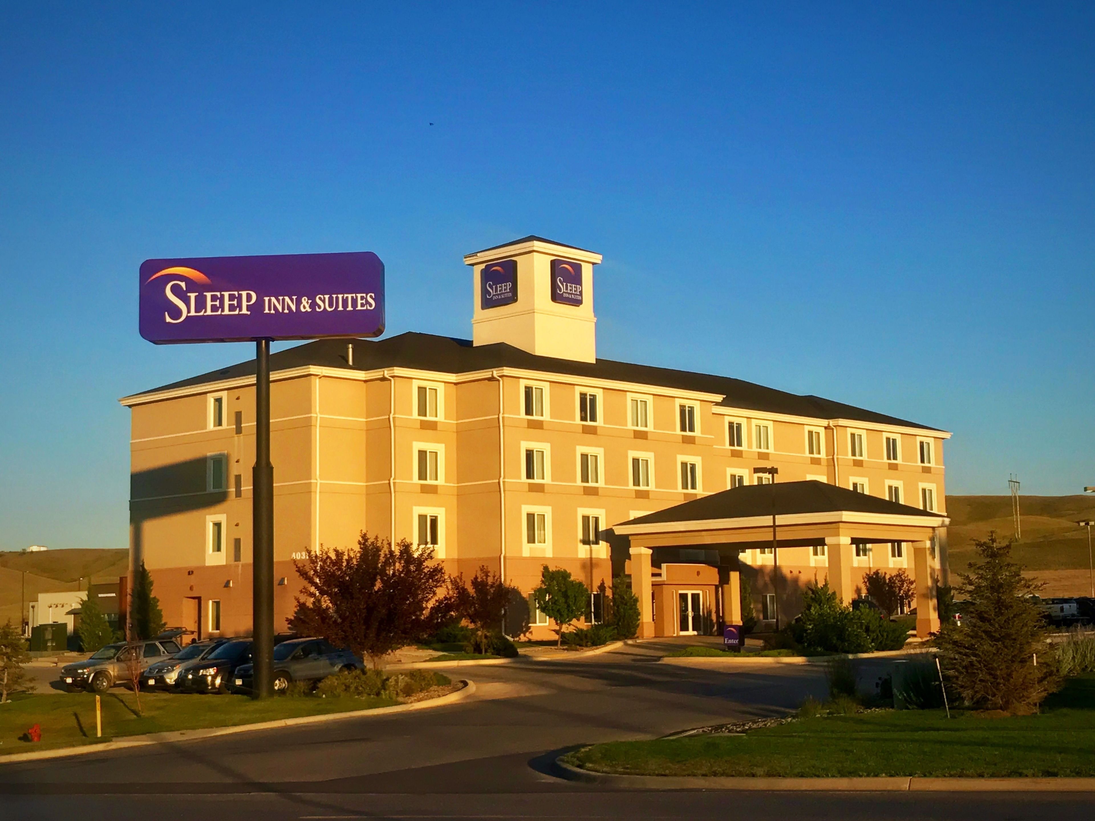 A Sleep Inn & Suites building with a large parking lot and a covered entrance.