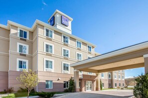 A multi-story hotel with a beige exterior, a covered entrance, and a sign indicating it is a Sleep Inn & Suites. - Sleep Inn & Suites Rapid City (Rapid City)