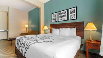 Habitación de hotel con una cama grande, dos mesitas de noche con lámparas, una silla y una pared decorada con cuadros.