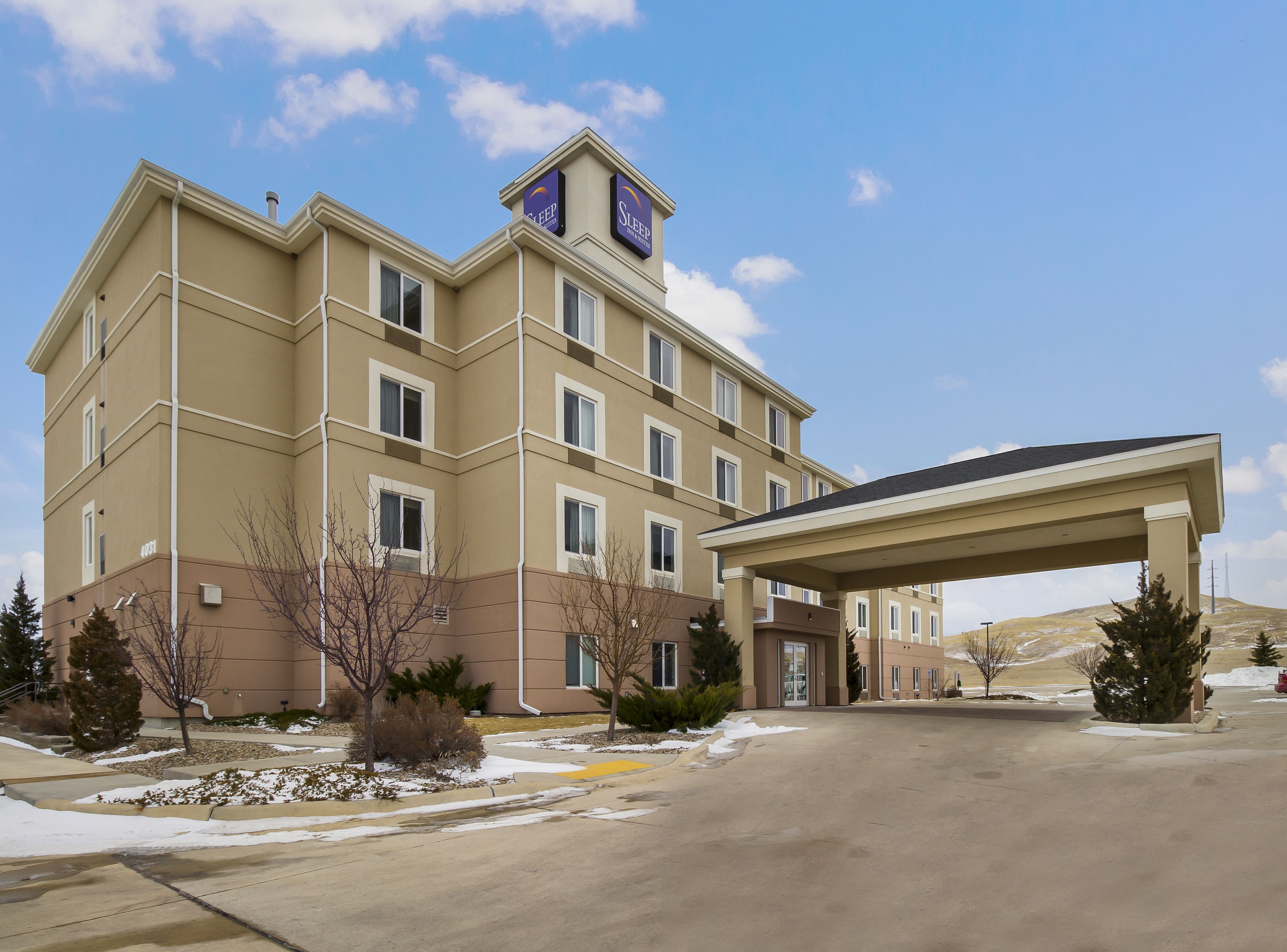 A multi-story hotel with a covered entrance and a parking area.