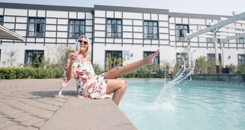 A person sitting by a pool with a building in the background.
