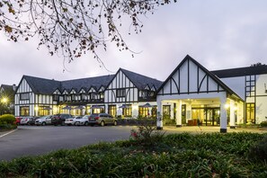 A hotel with a Tudor-style facade, a parking lot, and a well-lit entrance. - ANEW Hotel Hilton Pietermaritzburg (Hilton)