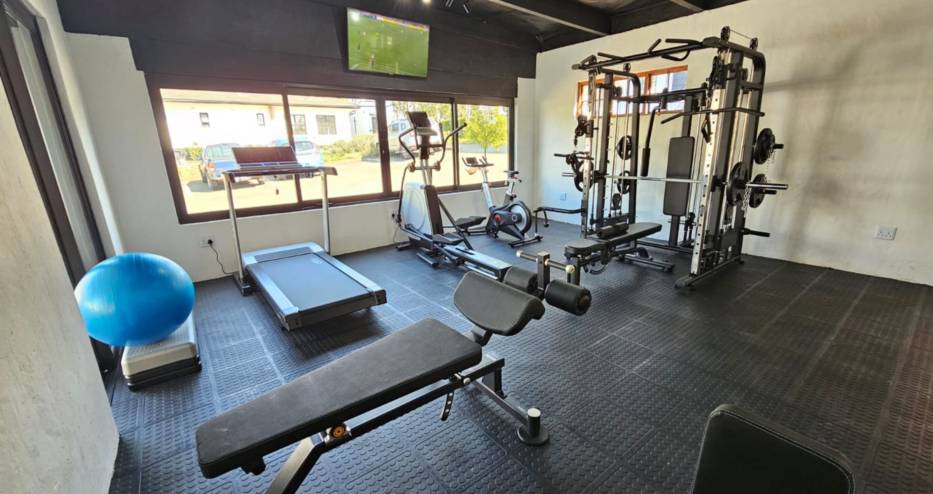 Ett gym med träningsredskap, ett löpband och en blå träningsboll.