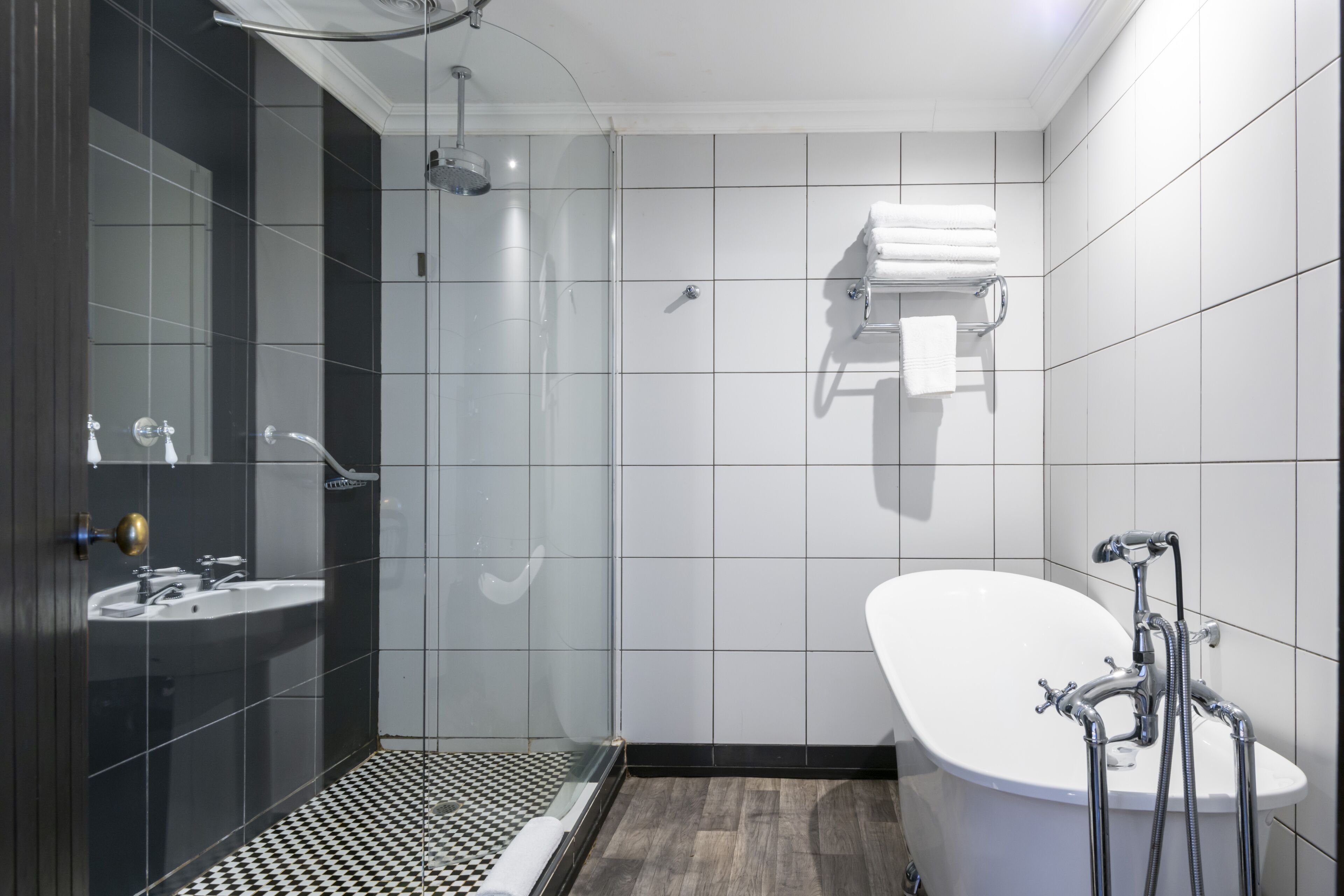 A modern bathroom with a glass-enclosed shower, a freestanding bathtub, and a sink with a mirror.