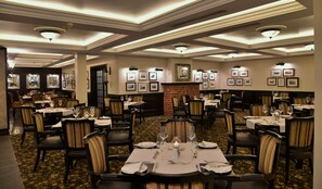 A formal dining area with tables set for service, framed pictures on the walls, and a patterned carpet. - ANEW Hotel Hilton Pietermaritzburg (Hilton)