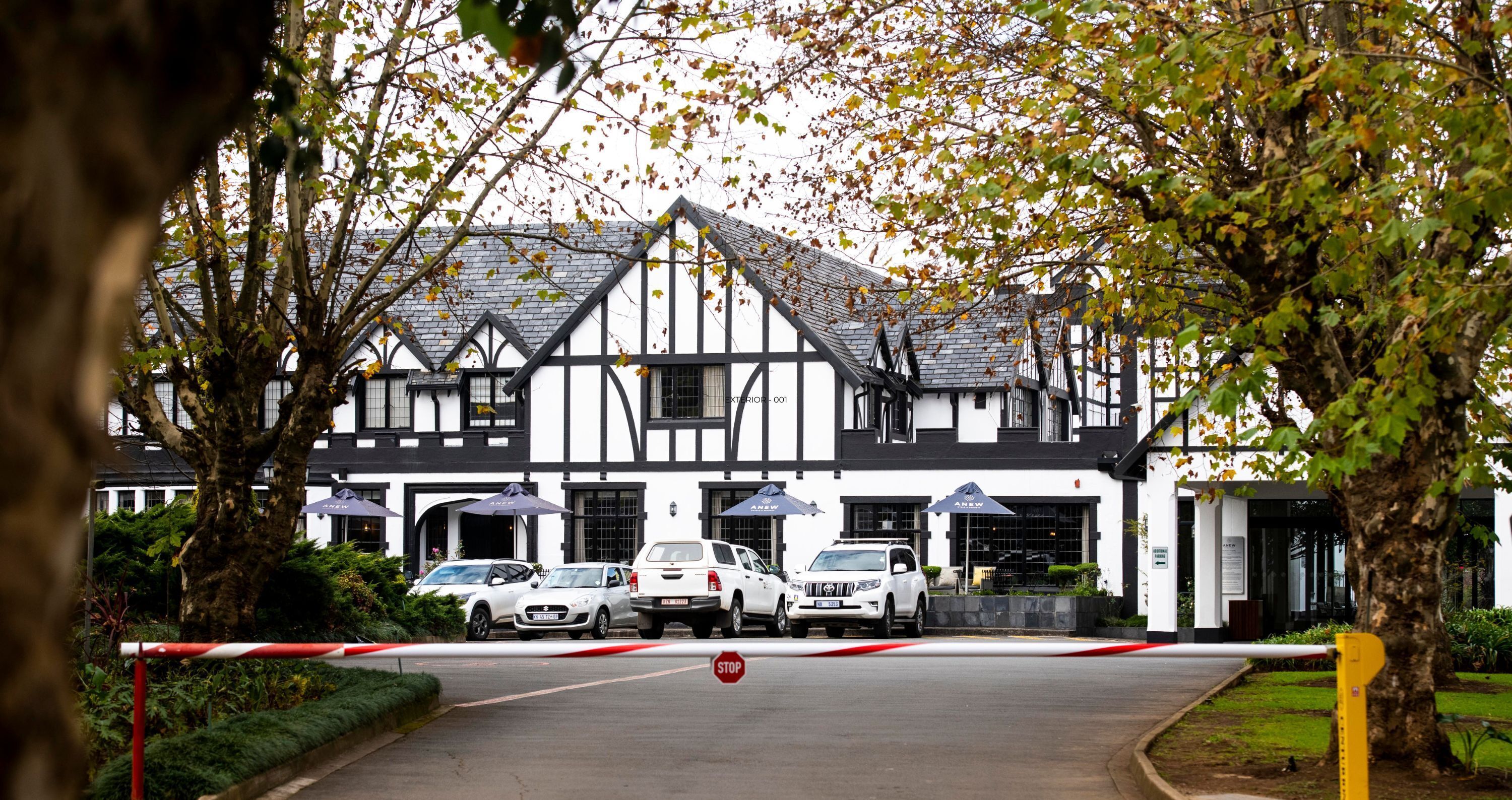 A traditional black-and-white building with a prominent entrance, a gated driveway, and parked cars.