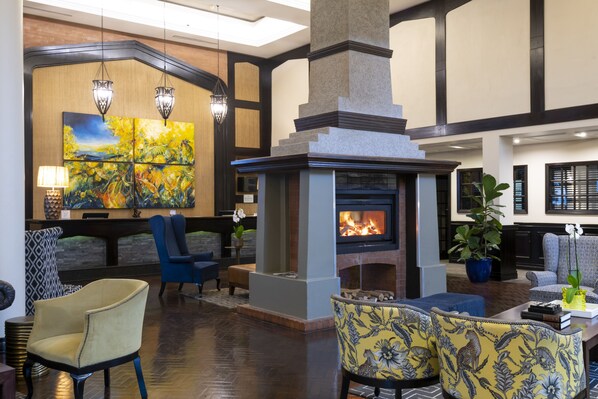 A lobby with a fireplace, comfortable seating, and artwork on the walls. - ANEW Hotel Hilton Pietermaritzburg (Hilton)