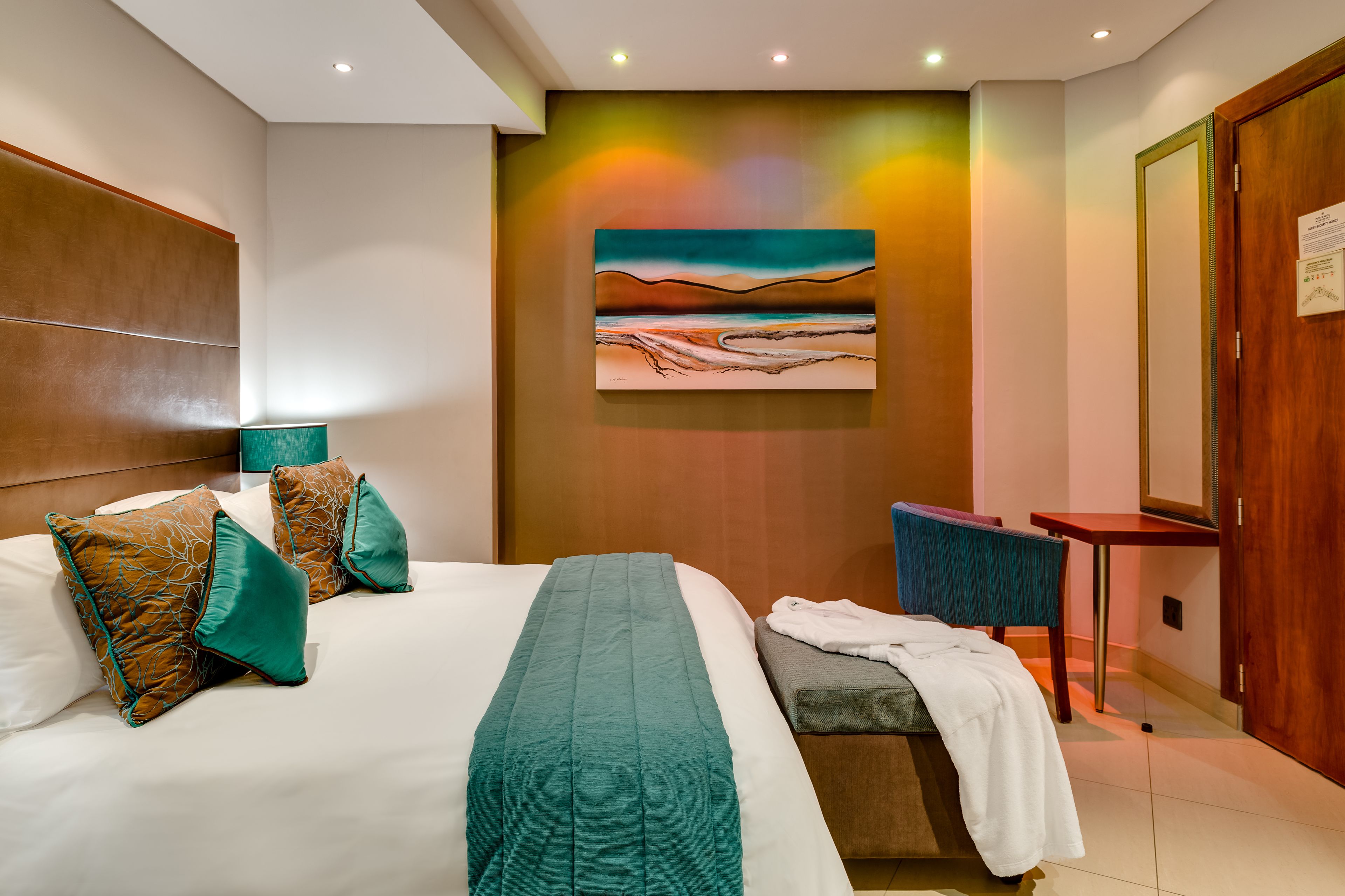 Una habitación de hotel con una cama grande, un escritorio y un cuadro en la pared.