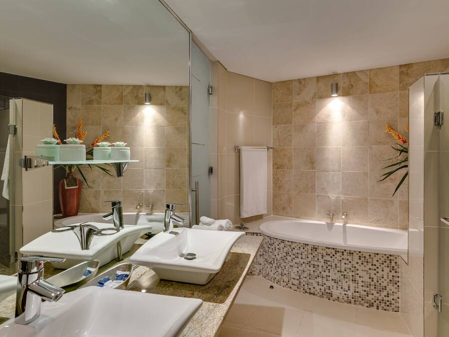 A modern bathroom with a large bathtub, multiple sinks, and a glass shower enclosure.