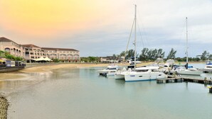 A marina with several boats docked, a building with multiple balconies, and a sandy beach area. - BON Hotel Waterfront Richards Bay (Richards Bay)