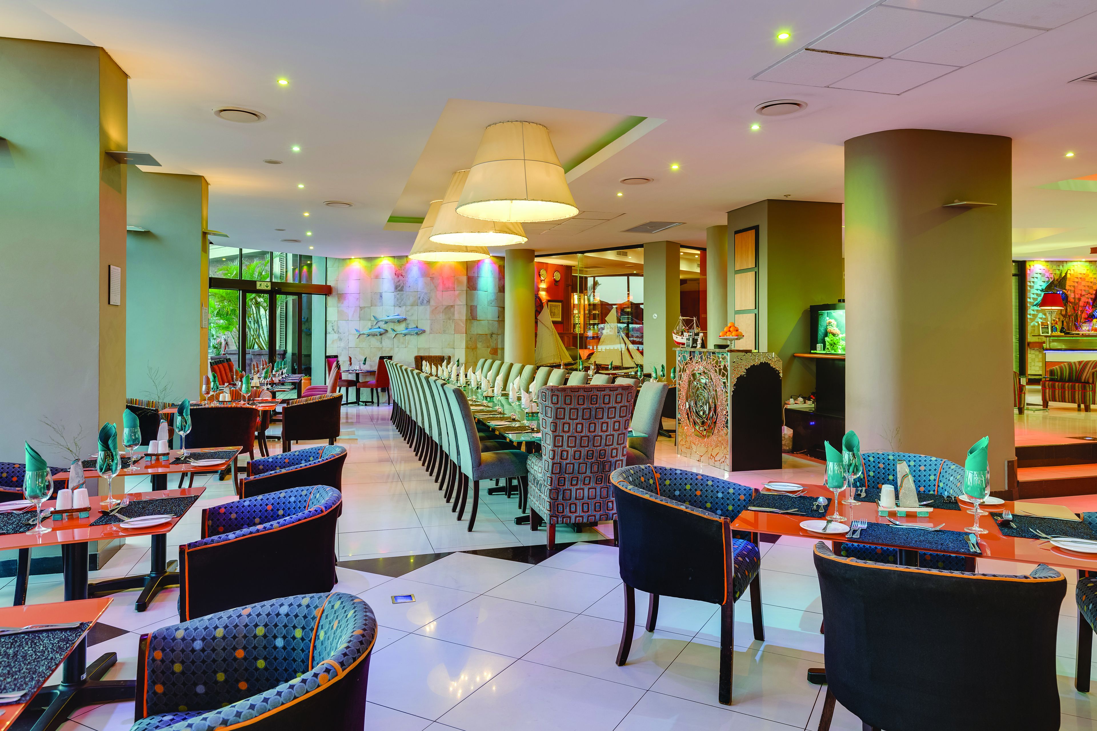 A spacious restaurant with multiple dining areas, including booths and tables, and a view of the outdoor area through large windows.