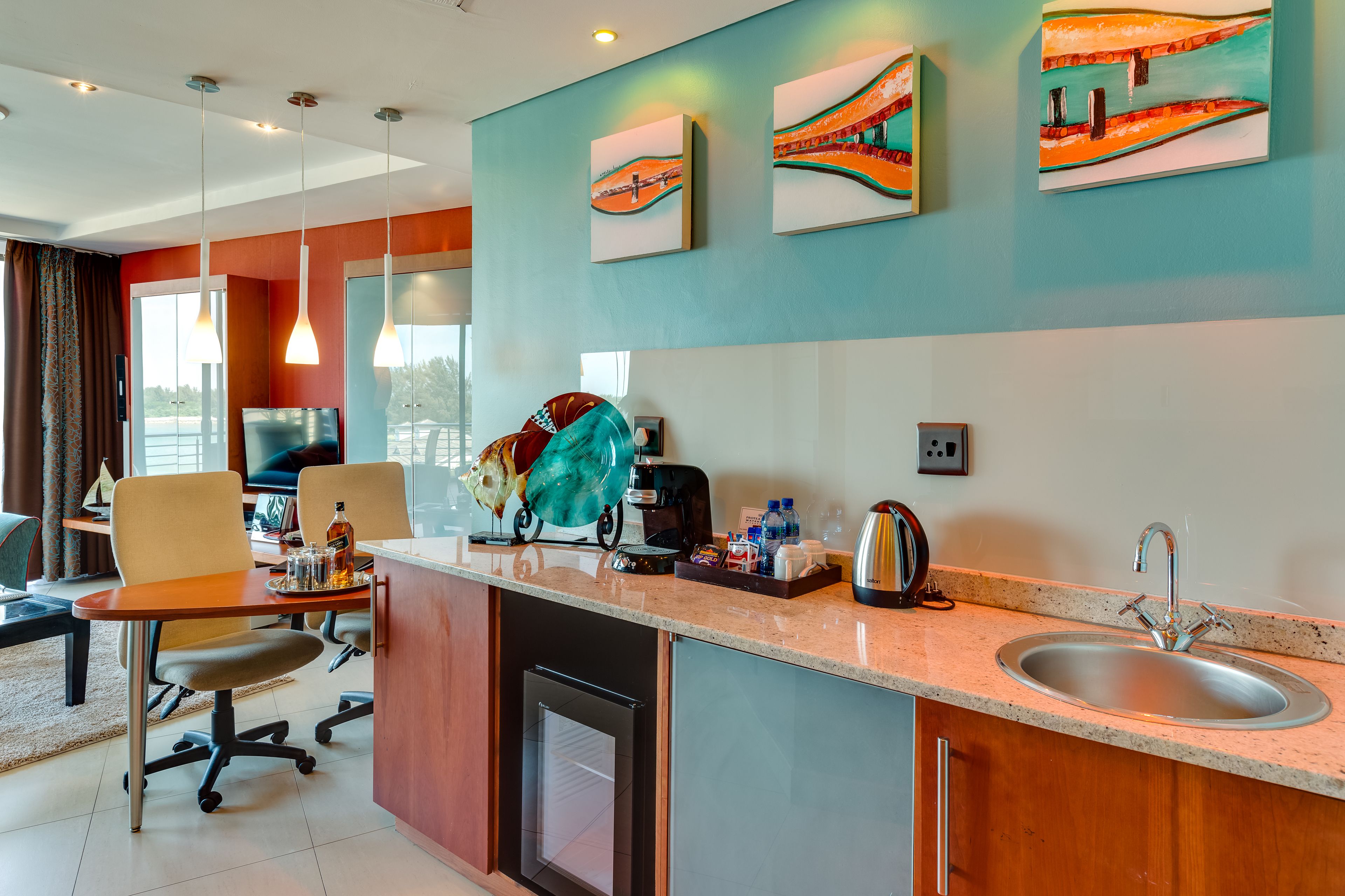A modern kitchen with a countertop, sink, and a coffee machine. There are two chairs and a dining table.