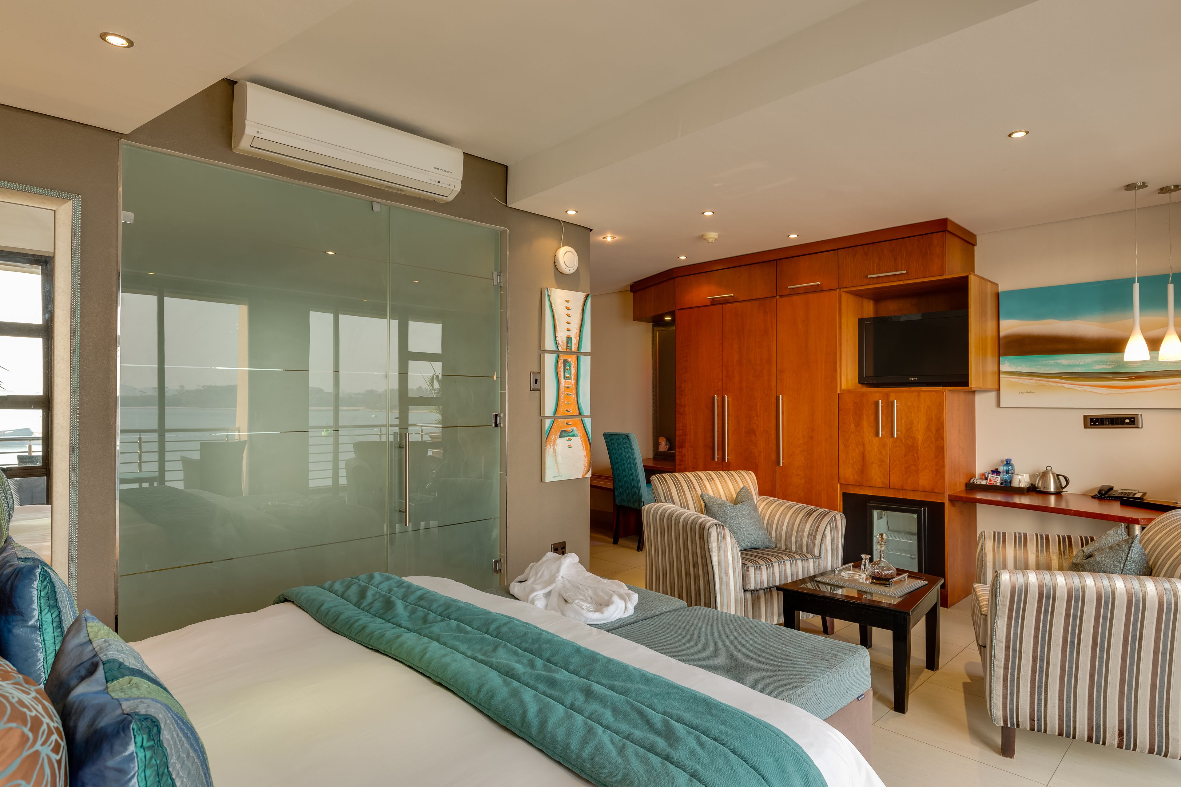 Une chambre d’hôtel dotée d’un grand lit, d’une télévision, d’un coin salon avec des fauteuils et d’une kitchenette.