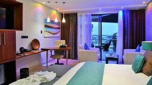 A hotel room with a bed, a desk, a chair, a TV, a painting, and a balcony with a view. - BON Hotel Waterfront Richards Bay (Richards Bay)