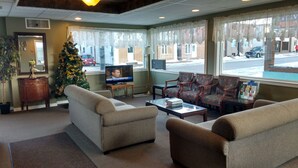 A cozy lobby with a Christmas tree, comfortable seating, and a television. - Travel Inn (Hearst)