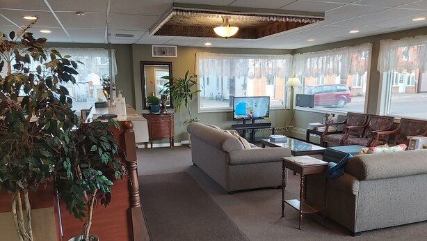 A spacious living area with a sofa, coffee table, and potted plants. - Travel Inn (Hearst)