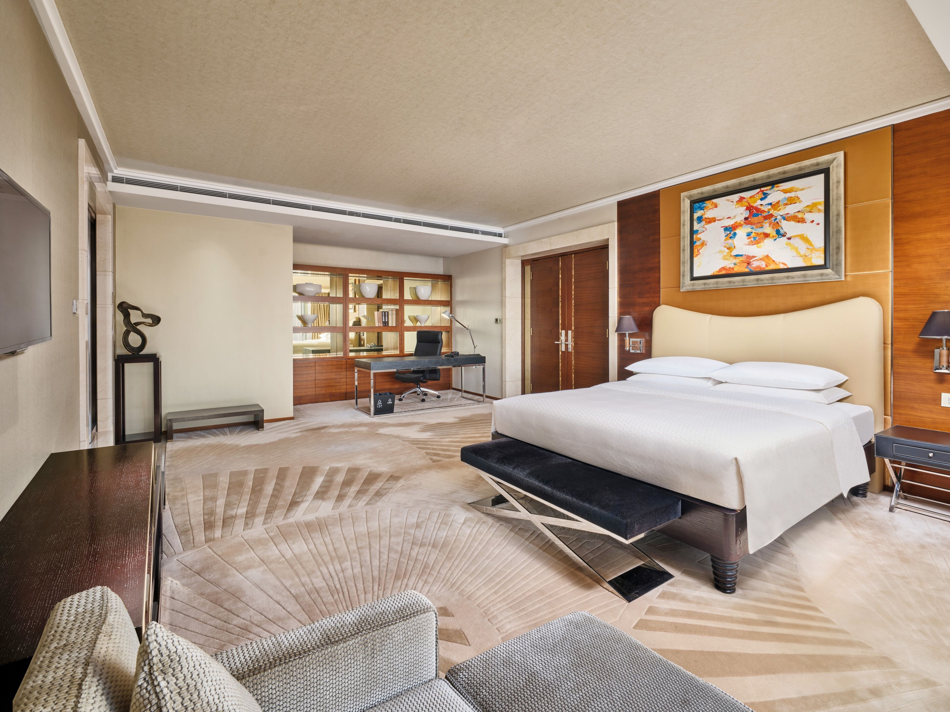 Een hotelkamer met een groot bed, een bureau, een stoel en een televisie.