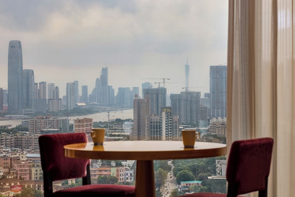 A table with two chairs in a room with a view of a cityscape.