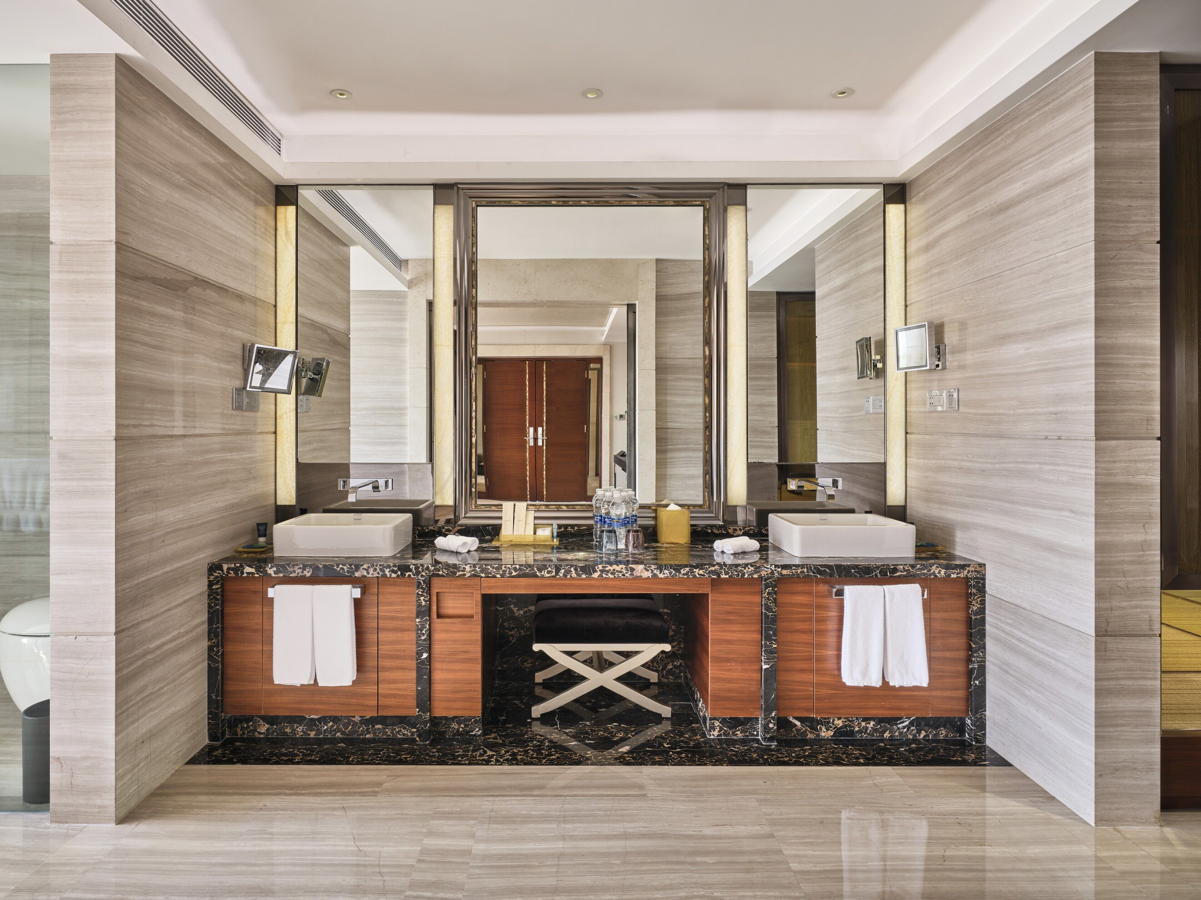 A modern bathroom with a large mirror, two sinks, and a vanity with a marble countertop.