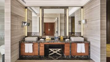 A modern bathroom with a large mirror, two sinks, and a vanity with a marble countertop.
