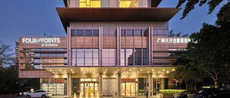 Um hotel de vários andares com design moderno, destacando uma entrada imponente com uma fonte e sinalização indicando ser um Four Points by Sheraton.